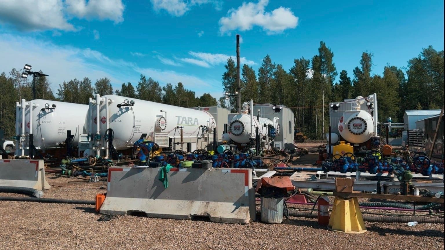 Pressure-rated flow lines, manifolds, and test equipment on an Alberta oilfield pad.
